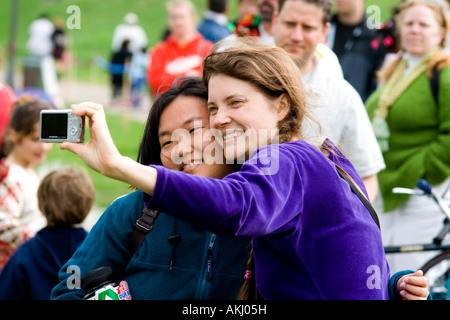 Woman age 30 making a self-portrait photograph. MayDay Parade and Festival Powderhorn Park. Minneapolis Minnesota USA Stock Photo