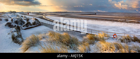 Panoramic image of Crosby beach after snowfall showing Mersey Estuary and Anthony Gormley's Iron Men Stock Photo