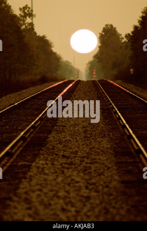A double set of railroad tracks lead to infinity and a firey sunset Stock Photo