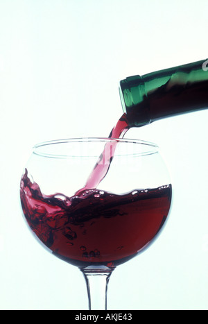 Abottle of red wine pouring into wine glass Stock Photo