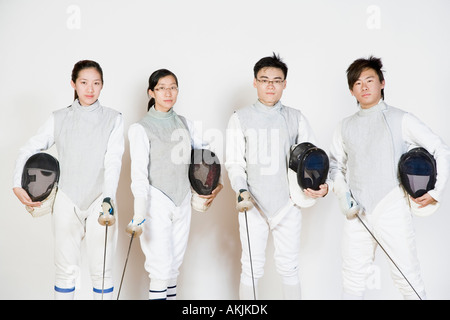 Portrait of two male and two female fencers holding fencing masks with fencing foils Stock Photo