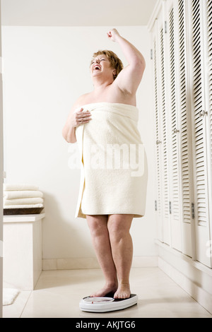 https://l450v.alamy.com/450v/akjtg6/happy-overweight-woman-on-bathroom-scale-akjtg6.jpg