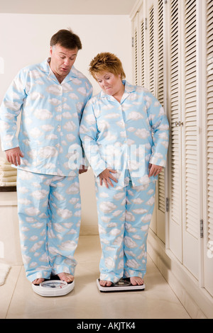Couple standing on bathroom scales Stock Photo