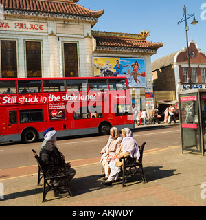 retired sikh people relaxing in sun opposite Himalaya Palace cinema house Southall London Stock Photo