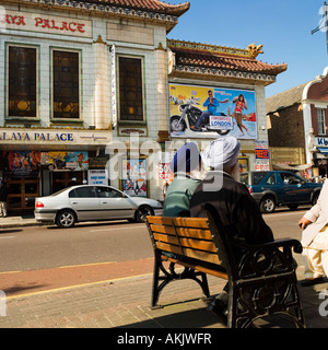 retired sikh men relax in sun opposite Himalaya Palace cinema house Southall London Stock Photo