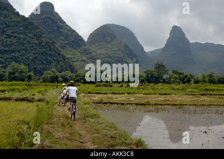 China Guangxi Yangshuo European Family Riding Bikes Along The Rice Paddies Stock Photo