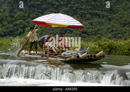China Guangxi Yangshuo A European Family On A Bamboo Raft Navigating On The Yulong River About To Pass A Dike Stock Photo