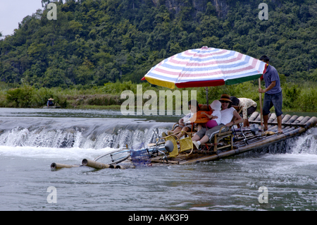 China Guangxi Yangshuo A European Family On A Bamboo Raft Navigating On The Yulong River Passing A Dike Stock Photo