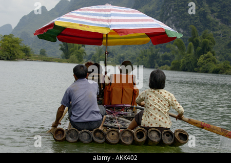 China Guangxi Yangshuo A Chinese Couple Rowing On A Bamboo Raft On The Yulong River With A European Family On Board Stock Photo