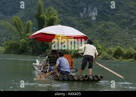 China Guangxi Yangshuo A Chinese Couple Rowing On A Bamboo Raft On The Yulong River With A European Family On Board Stock Photo