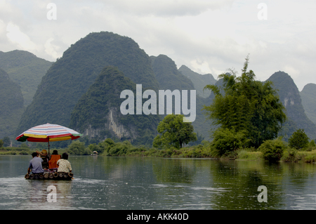 Chinese couple rowing a bamboo raft along the Yulong River with a European family on board, Yangshuo, Guangxi, China. Stock Photo