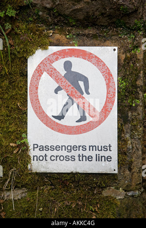 Safety sign on railway platform 'Passengers must not cross the line' Stock Photo