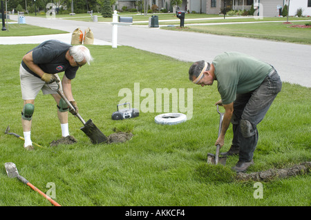 2 late middle age men do lawn irrigation as a second career Stock Photo