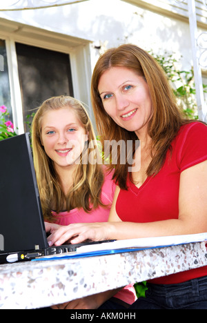 Mother and daughter working on a portable computer at home in the garden Stock Photo