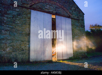 Barn doors slightly open, smoke and light coming out. Stock Photo