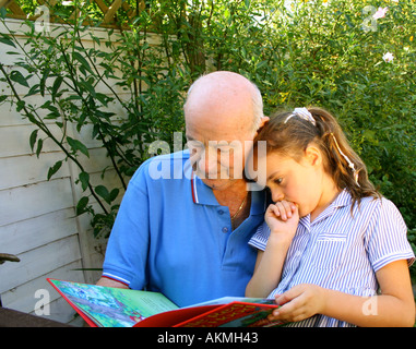 Child Reading with her Grandad Stock Photo