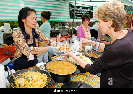 Women serving noodles on a stall at the annual food festival in Abergavenny Monmouthshire Wales UK GB Stock Photo