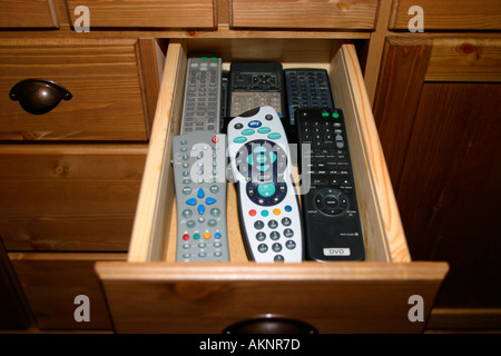 Sideboard drawer with many remote control unit handsets Stock Photo