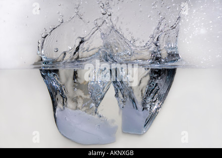 High speed flash of a pair of ice cubes splashing when dropped into water Stock Photo