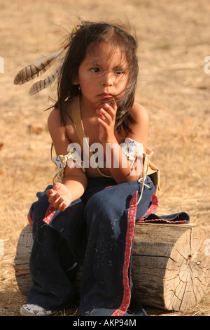 Young Native American boy sitting on a log looking distraught or upset Stock Photo