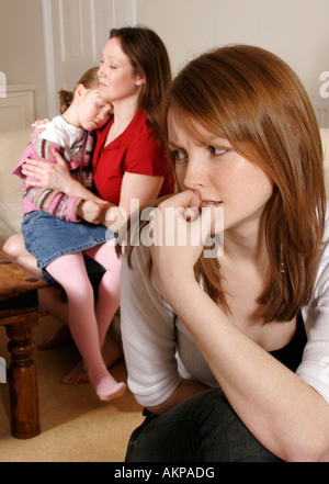 Mother comforting little girl and concerned young woman in foreground Stock Photo