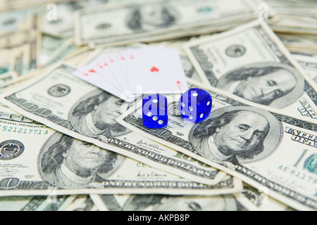 Cards and blue dice on top of pile of one hundred dollar bills Stock Photo