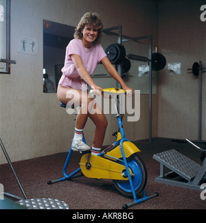 girl makes stamina training on a bicycle, gymnastics, young woman, floor exercises, health training, power training, fitness centre, health club, exercise room, fun, funny, beaming with happiness, joy, pleasure, health, leisure, leisure time, free time, b Stock Photo