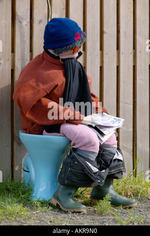 Annual village scarecrow competition in Thornhill near Stirling, Scotland. Man sitting on toilet reading newspaper Stock Photo