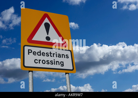 YELLOW PEDESTRIAN CROSSING SIGN AGAINST BLUE SKY WITH WHITE CLOUDS Stock Photo