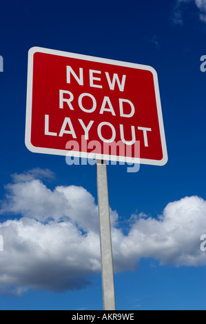 RED NEW ROAD LAYOUT WARNING SIGN WITH BLUE SKY AND WHITE CLOUDS IN BACKGROUND Stock Photo