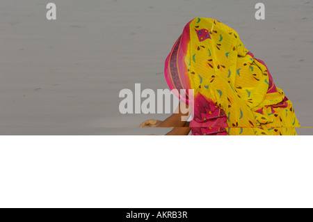 Rabari woman wearing their everyday dress and jewellery while washing her brass water pot in the salt pans. Gujarat Stock Photo