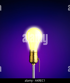 lightbulb glowing against blue background Stock Photo