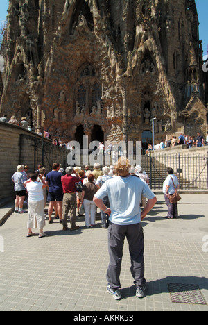 Group of tourists people outside long running construction building site of Roman Catholic church the Basílica de la Sagrada Família   Barcelona Spain Stock Photo