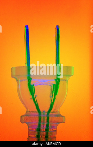 Clear Electric Plug lit with blue and green against a red and yellow gradient background Stock Photo