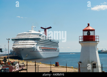 Stock image of a Carnival line cruise ship at Pugley s Wharf with Coast Guard lighthouse in Sain John New Brunswick Canada Stock Photo