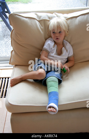 Little boy with a broken leg sitting on a bench Stock Photo