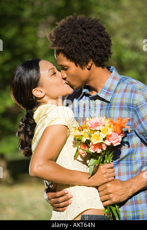 Woman and man embracing and kissing in park Stock Photo
