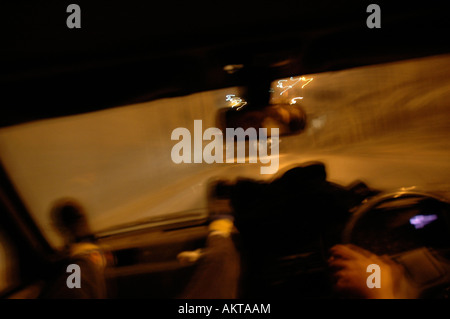 A shot taken from inside a moving car looking through the front windscreen window with a passenger and the driver visible Stock Photo