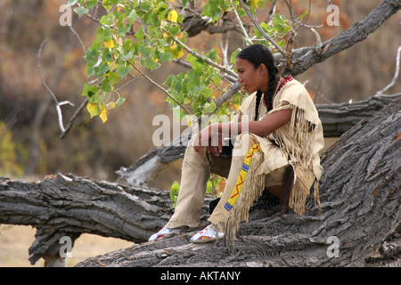 A teenager Native American Indian boy sitting on a downed tree Stock Photo