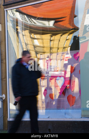 Man using mobile phone with reflections in shop window behind Morecambe Lancashire Stock Photo