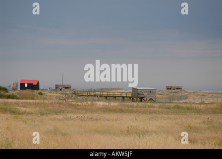 Red roofed and black corrugated iron hut wooden bird watching hide and concrete second world war bunkers on the shingle Stock Photo