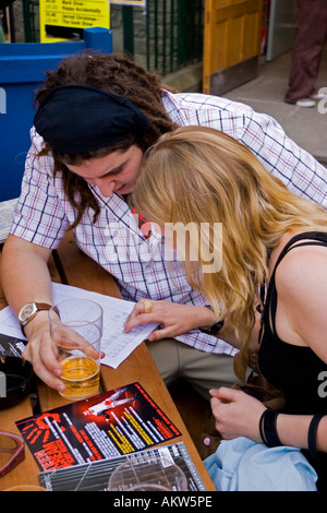 Man and woman study the entertainment programme at Pleasance Courtyard during the Edinburgh Fringe Festival Scotland UK Stock Photo