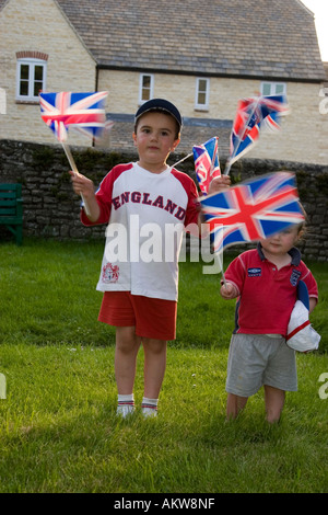 Boy and girl wearing England football shirts and waving England flags