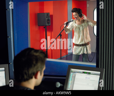 Young woman singing in studio, technician in foreground Stock Photo