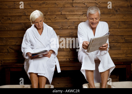 Germany, senior couple reading magazine in spa Stock Photo