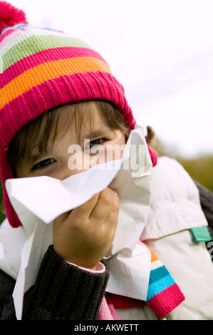 Girl (4-5) blowing nose, close-up Stock Photo