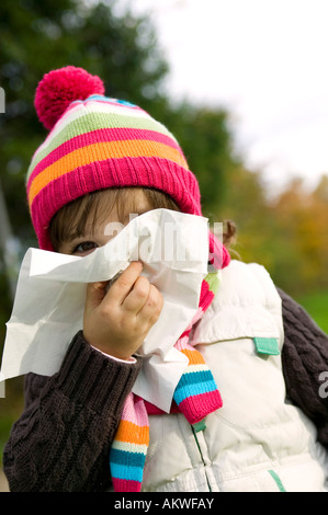 Girl (4-5) blowing nose, close-up Stock Photo