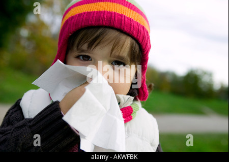 Girl (4-5) blowing nose, close-up Stock Photo