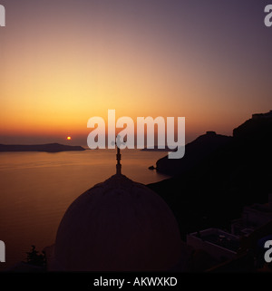 Classic sunset with view to Thirasia Island over domed church with cross on top at Fira on Santorini The Greek Islands, Greece Stock Photo