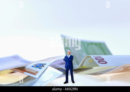 Businessman figurine, money in background, close-up